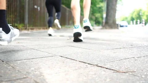 Close-up shot of four people jogging down the street Stock Footage 114884524