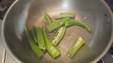 Close up shot of frying green chilli in a cauldron or frying pan. Stock Footage 282567466