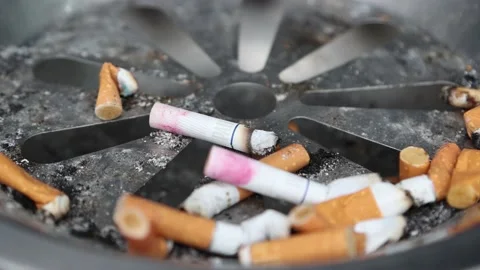 Close up shot of a full ash tray and several cigarettes still burning in it Vidéo 148049451