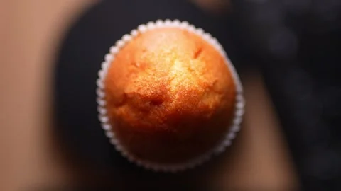 A close-up shot of a golden-brown muffin in a white paper wrapper Stock Footage 328599366