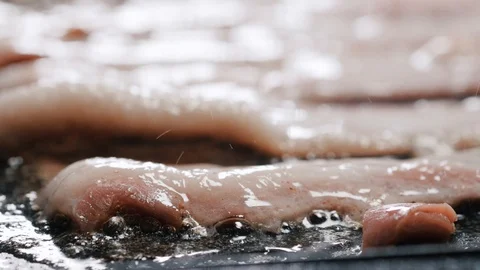 Close up shot of greasy bacon strips being cooked on the hot oil Stock Footage 102569904