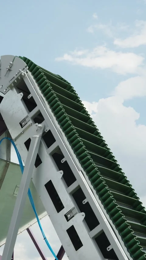 A close-up shot of a green cleated conveyor belt with wavy corrugated Stock Footage 339910646