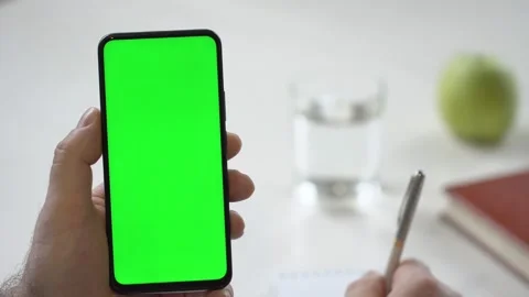 Close-up shot of green screen template smartphone in male hands at home offise Stock Footage 142877056