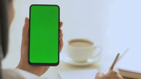 Close-up shot of green screen template smartphone in female hands at home offise Stock Footage 142877436