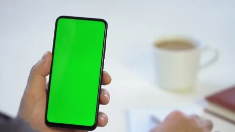 Close-up shot of green screen template smartphone in male hands at home offise Stock Footage 143590656