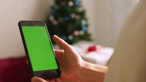 Close-up shot of green screen template smartphone in hands in Christmas interior Stock Footage 164584483