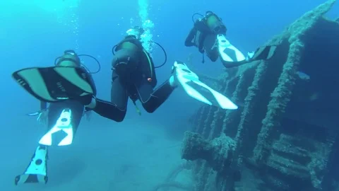 Close shot of a group of divers with an instructor explore the wreckage Stock Footage 79399651