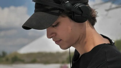 A close-up shot of a guy making music at a DJ set in the middle of a desert Stock Footage 172294427
