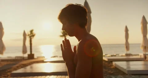 Close-up shot of a guy meditating on a sunny beach in the morning Stock Footage 249843835