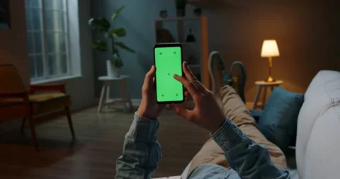 Close up shot of guy relaxing on couch at night, using smartphone with chroma Stock Footage 136478241