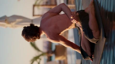 Close-up shot of a guy stretching his legs and meditating on a special private Stock Footage 249234846