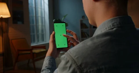 Close up shot of guy using his smart phone with mock up green screen at night Video stock 127469923