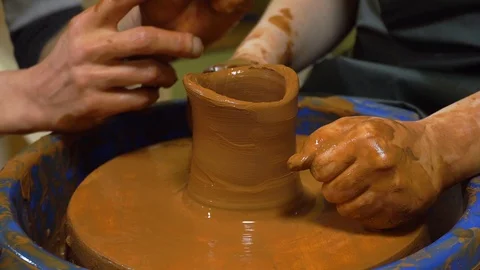 Close-up shot of half-finished ceramic vase spinning on potters's wheel and hand Stock Footage 99772456