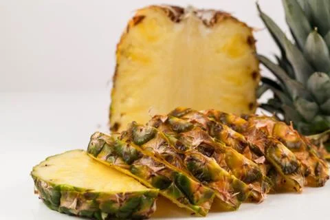 CLose-up shot of half of pineapple and slices of it placed on a white background Stock Photos