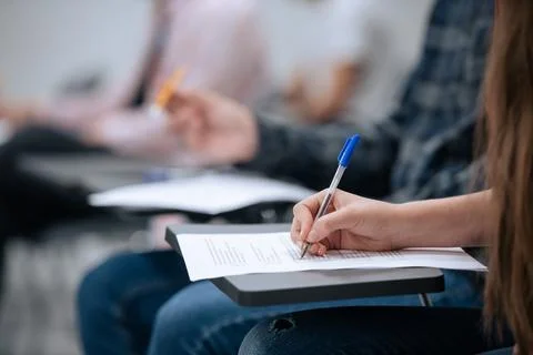 A close-up shot of a hand and a sheet of paper on which a student takes notes Stock Photos