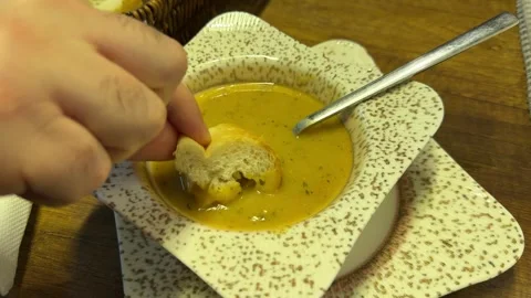 Close-up shot of a hand dipping fresh bread into a bowl of lentil soup Vídeos de archivo 340154960