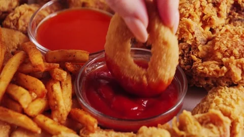 Close-up shot of hand dipping onion rings into ketchup. Tasty set of french Stock Footage 329278090