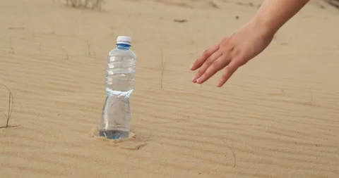 Close up shot, hand grabbing small plastic bottle, clear, clean water in desert 動画素材 176312053