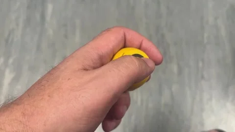 A close-up shot of a hand holding a small, round, yellow portable Bluetooth.. Stock Footage 323007717