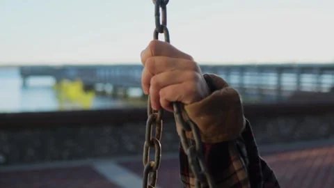 Close-up shot of a hand holding a swing chain, with a soft-focus view... Stock Footage 322811877