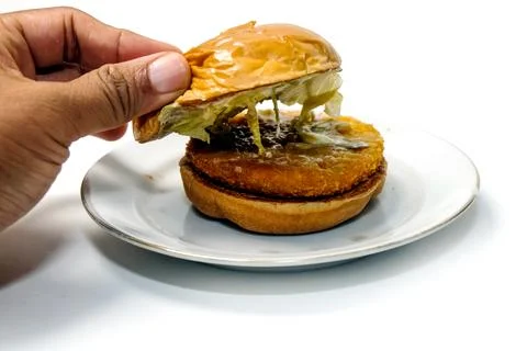Close-up shot of a hand lifting the top bun of a crispy chicken burger to r.. 스톡 사진