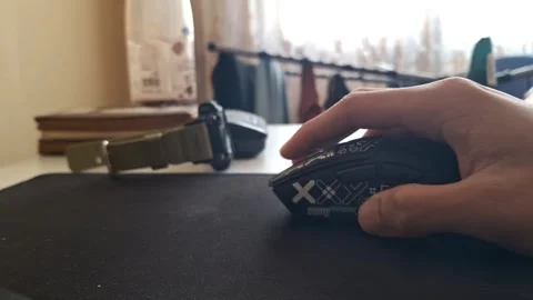 Close-up shot of a hand operating a black ergonomic gaming mouse on a mousepad Stock Footage 329748339