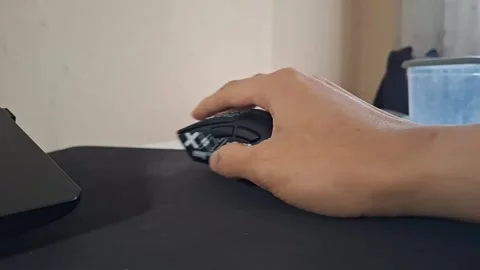 Close-up shot of a hand operating a black ergonomic gaming mouse on a mousepad Stock Footage 329748340