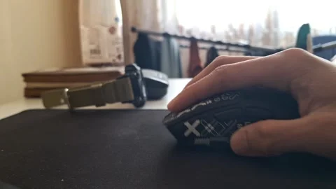 Close-up shot of a hand operating a black ergonomic gaming mouse on a mousepad Stock Footage 329748977