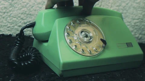 Close-up shot hand picking up the receiver of a vintage green rotary telephone Stock Footage 337049394