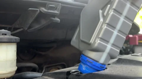 A close-up shot of a hand pouring fresh engine oil into a car's engine Stock Footage 312586314