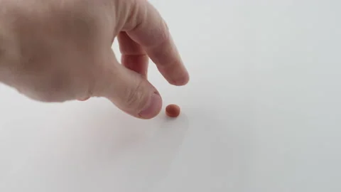 Close up shot of a hand reaching in to pick up a little red pill Video stock 153073994