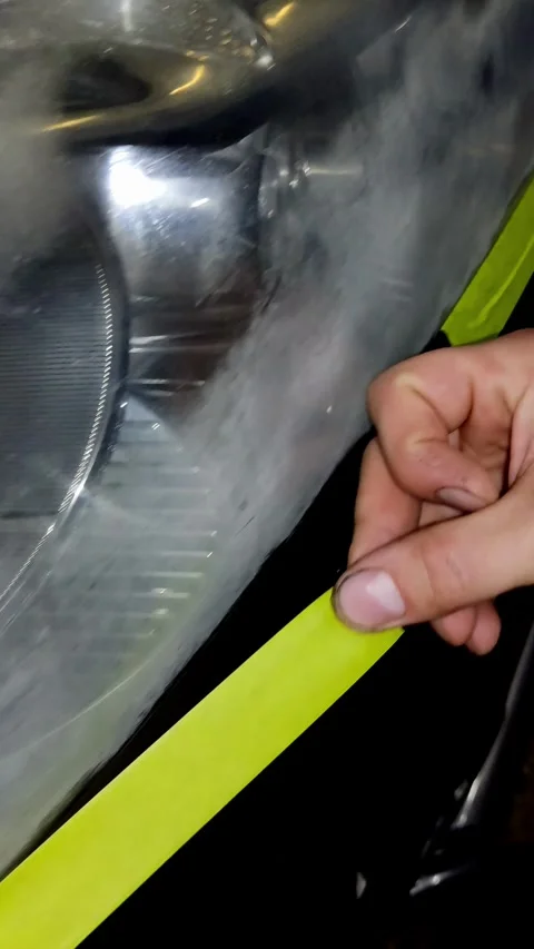 A close-up shot of a hand removing yellow tape from car headlight Stock Footage 336274640