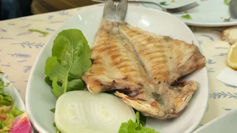 Close-up shot of hand squeezing fresh lemon over a grilled sea bass dish Stock Footage 340155043