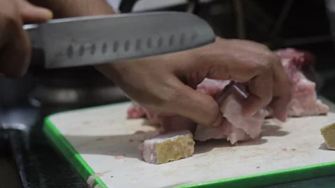 A close-up shot of a hand using a knife to cut thick pieces of fat of pork. Stock Footage 279134431