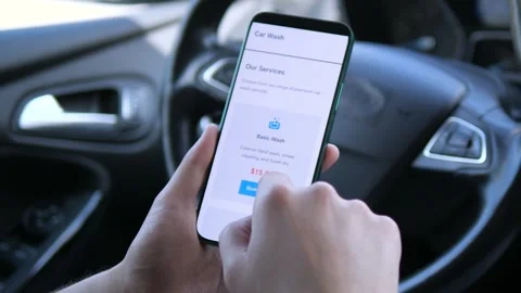 Close-up shot of hands in a car interior navigating a car care service app on a Stock Footage 315029961