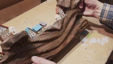 A close-up shot of hands carefully arranging miniature wooden houses Vídeo Stock 333149681