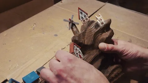 A close-up shot of hands carefully arranging miniature wooden houses Vídeo Stock 333149684