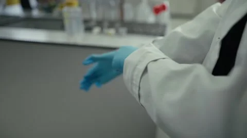 A close-up shot of hands carefully putting on medical gloves in a professional Stock Footage 337602486
