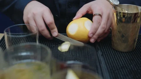 Close-up shot of hands cutting a grapefruit on a bar mat beside metal bar tools Stock Footage 333675701