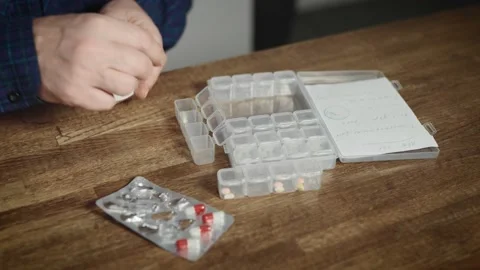 In a close-up shot, the hands of an elderly man who arranges medicines in an Stock Footage 236401338