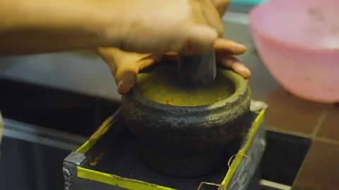 Close-up shot of hands grinding palm kernel fruit shells with mortar and 스톡 동영상 252569105