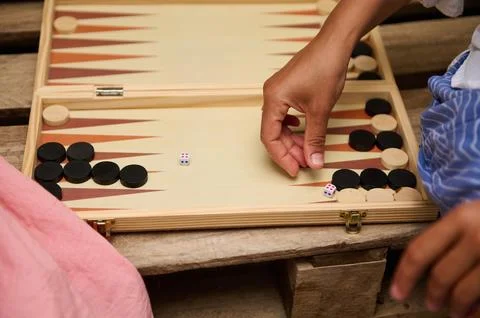 A close-up shot of hands moving pieces on a backgammon board, focusing on gam Stock Photos