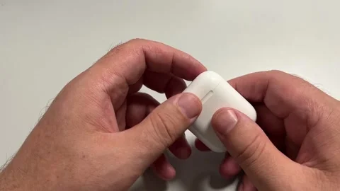 A close-up shot of hands opening a small, white plastic charging case to re.. Stock Footage 323058850