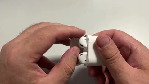 A close-up shot of hands opening a small, white plastic charging case to re.. Stock Footage 323058854