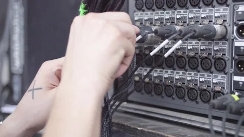 Close-up shot of hands plugging XLR cables into a multi-channel panel Stock Footage 258336632