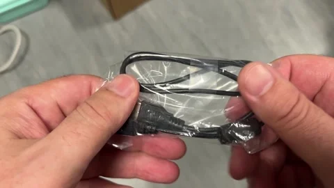 A close-up shot of hands pulling a coiled, black braided charging or data c.. Stock Footage 323139861