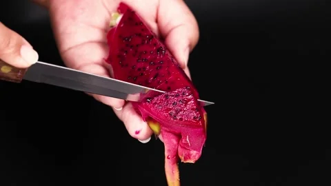 Close up shot of hands slicing a red dragon fruit with black seeds using a .. Vídeo Stock 332586160