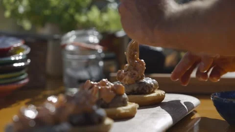 Close-up shot of hands stack patty and cheese topping on top of soft buns Stock Footage 247054716
