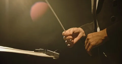 Close up shot of hands of symphony orchesra conductor directing music by waving Stock Footage
