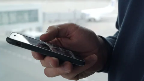 Close-up shot of hands using smartphone to send text messages inside exit gate Stock Footage 165410752